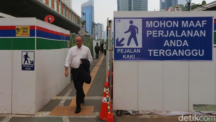 Kawasan proyek MRT Bundaran HI yang biasanya identik dengan hiruk-pikuk alat berat dan konstruksi kini menghadirkan pemandangan yang tak biasa. Sebuah trotoar darurat yang dibangun untuk mengalihkan pejalan kaki selama masa pembangunan disulap menjadi lorong hijau bertema taman labirin yang memukau. Dekorasi unik ini langsung mencuri perhatian warga Jakarta yang melintas, mengubah jalur sementara itu menjadi spot foto dadakan yang ramai di media sosial.