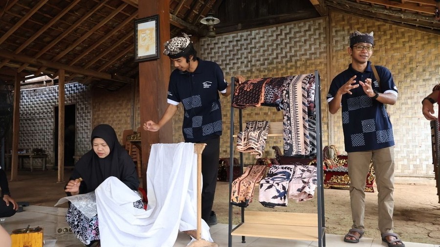 Suara lesung kayu bergema berirama di halaman rumah tradisional Osing, menandai kehidupan yang terus berdenyut di Desa K